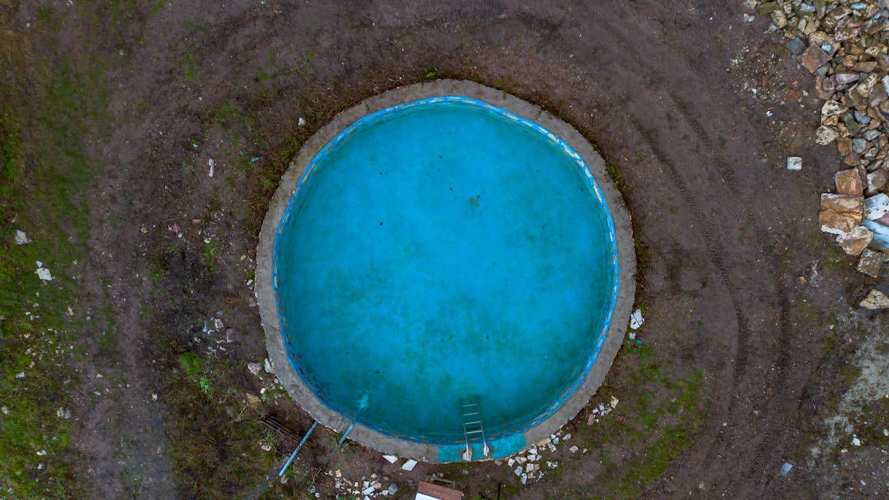Circular empty water tank with turquoise liquid captured from above in Velmevtsi, North Macedonia.